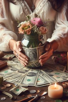 a woman sitting at a table with money and flowers in a vase on top of it