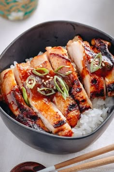 some meat and rice in a bowl with chopsticks