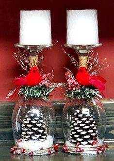 two glass vases with pine cones and red birds on them