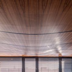 the interior of a modern house with wood slats on the ceiling and large windows