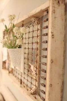 a vase with flowers is hanging on the wall next to an old window sill