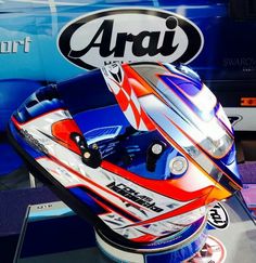 a motorcycle helmet on display in front of a blue van with the name arai written on it