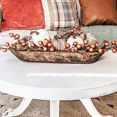 a basket filled with pumpkins sitting on top of a white table next to pillows