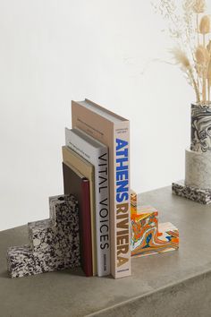 three books are stacked on top of each other in front of a vase with flowers