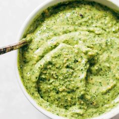 a white bowl filled with green sauce on top of a table