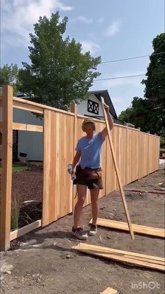 a person standing in front of a wooden fence with a hammer and some wood planks