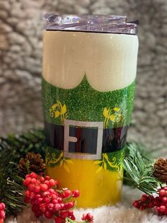 a green and white frosted cup sitting on top of a pile of pine cones