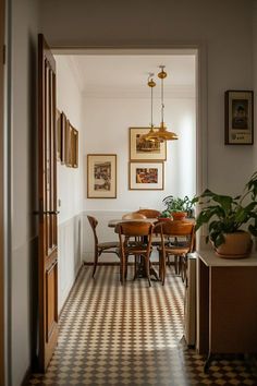 a hallway leading to a dining room with checkered flooring and potted plants