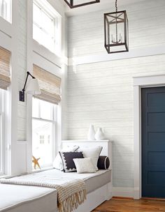 a window seat in a room with white walls and wood flooring, two lanterns hanging from the ceiling