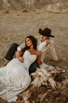 a man and woman in cowboy hats sitting on the ground next to a dead animal