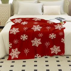 a bed covered in a red and white blanket with snowflakes on it