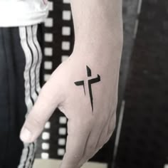 a person's hand with a cross tattoo on it