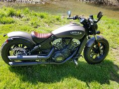 a motorcycle is parked in the grass near a river