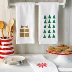 two tea towels with trees on them are hanging from the kitchen towel rack next to plates and bowls