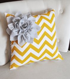 a yellow and white pillow with a flower on the front, sitting on a couch