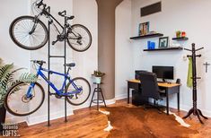 there is a bike hanging on the wall next to a desk with a computer and chair