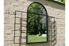 an arched window is shown in front of a brick wall with a mirror on it