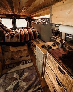 the interior of an rv with wood floors and walls, including a bed in the center