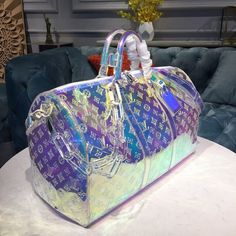 Description   L.V Keepall Bandouliere 50 Monogram PVC Iridescent Prism By Virgil Abloh For Men, Bags, Travel Bags 19.7in/50cm LV M53271  Rep 1:1     One of the most highly sought after pieces from Virgil Abloh’s men’s Spring Summer 2019 collection, this holographic coated keepall is already a cult favorite. The duffle features the iconic LV monogram print against an iridescent clear and pink coated canvas. An adjustable crossbody strap is included for optimal comfort and support. Attached to the top handle is a lucite chain link for a street-meets-luxury vibe.     50 x 29 x 23 cm / 19.7 x 11.4 x 8.7 inches (Length x height x width)   Iridescent Prism  Transparent embossed Monogram PVC  PVC trim  White hardware  Top handle for hand or elbow carry  Handle fastener  Double zip closure  Covere Clothing Painting, Louis Vuttion, Sac Louis Vuitton, Luxury Luggage, Pvc Trim, Luxury Bags Collection, Girly Bags, Louis Vuitton Keepall, Handbag Heaven