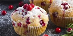 three cranberry muffins with powdered sugar and berries on the table