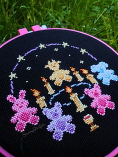 a close up of a cross - stitch pattern on a black cloth with pink trim