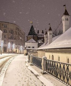 a snow covered street with buildings in the background