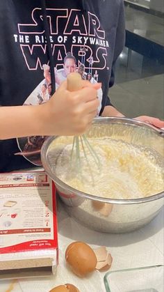 a young boy mixing ingredients in a bowl on top of a table with an egg carton