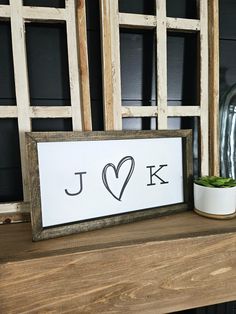 a wooden sign with the word j is displayed next to a potted plant on a shelf