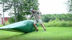 a man standing next to a large green object on top of a lush green field