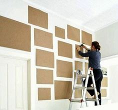 a woman is painting a wall with brown squares on it and she is using a paint roller