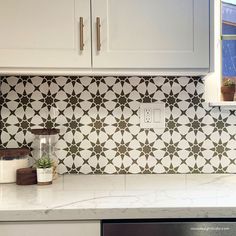 a white kitchen with black and white tiles on the backsplash, counter tops and cabinets