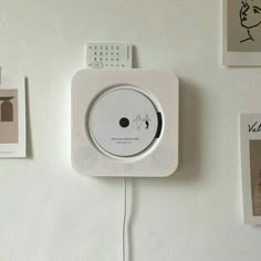 a white clock mounted to the side of a wall next to pictures and magnets