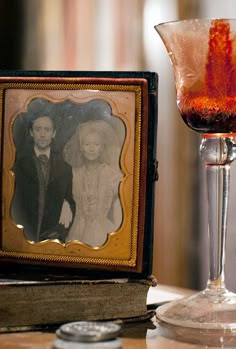 an old fashioned photo is next to a wine glass with a red liquid in it