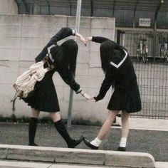 two young women in school uniforms are walking down the street with their arms around each other