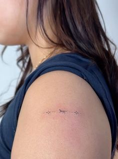 the back of a woman's shoulder with an arrow tattoo on her left arm