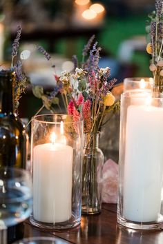 three vases filled with white candles sitting on top of a table