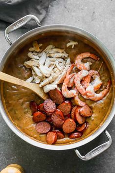 a pot filled with shrimp, sausage and grits next to an orange peel on the side