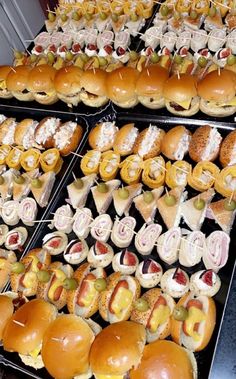 several trays filled with different types of sandwiches