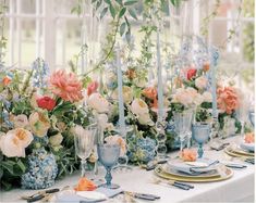 the table is set with blue and white dishes, silverware, and floral centerpieces