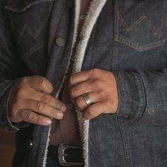 a man in a denim jacket is holding onto his wedding band and wearing a ring