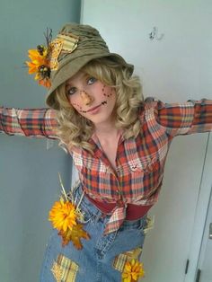 a woman in overalls and a hat with sunflowers on her head is posing for the camera