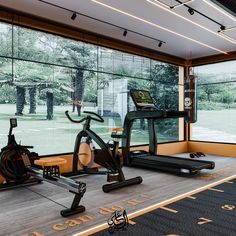 an exercise room with treadmills and other equipment in front of large glass windows