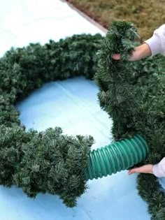 a person is holding a green hose near a wreath