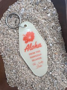 an aloha keychain is laying on the ground next to some gravel