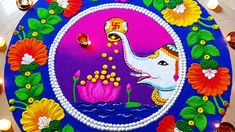 an elephant painted on the side of a blue plate with candles around it and flowers