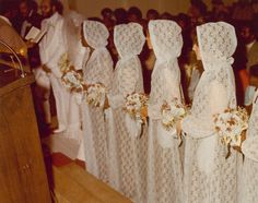 a group of women in white dresses standing next to each other near a podium with flowers on it