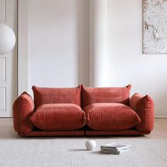 a red couch sitting on top of a white rug