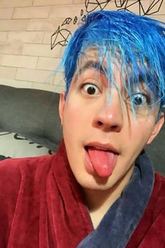 a man with blue hair sticking his tongue out and making a funny face at the camera