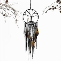 a wind chime with feathers hanging from it's side and branches in the background