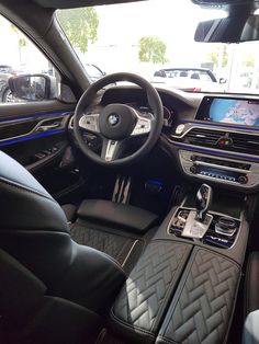 the interior of a bmw car with black leather seats and blue stitching on the dash